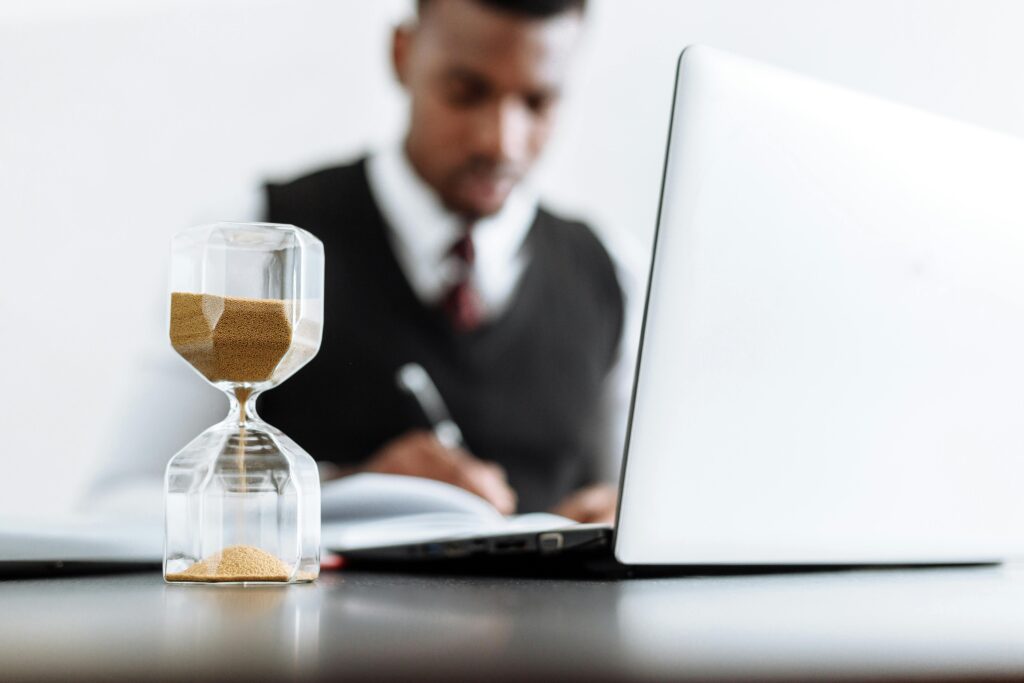 pexels-photo-5060979-5060979 Businessman at desk with hourglass indicating time management and daily work routine.