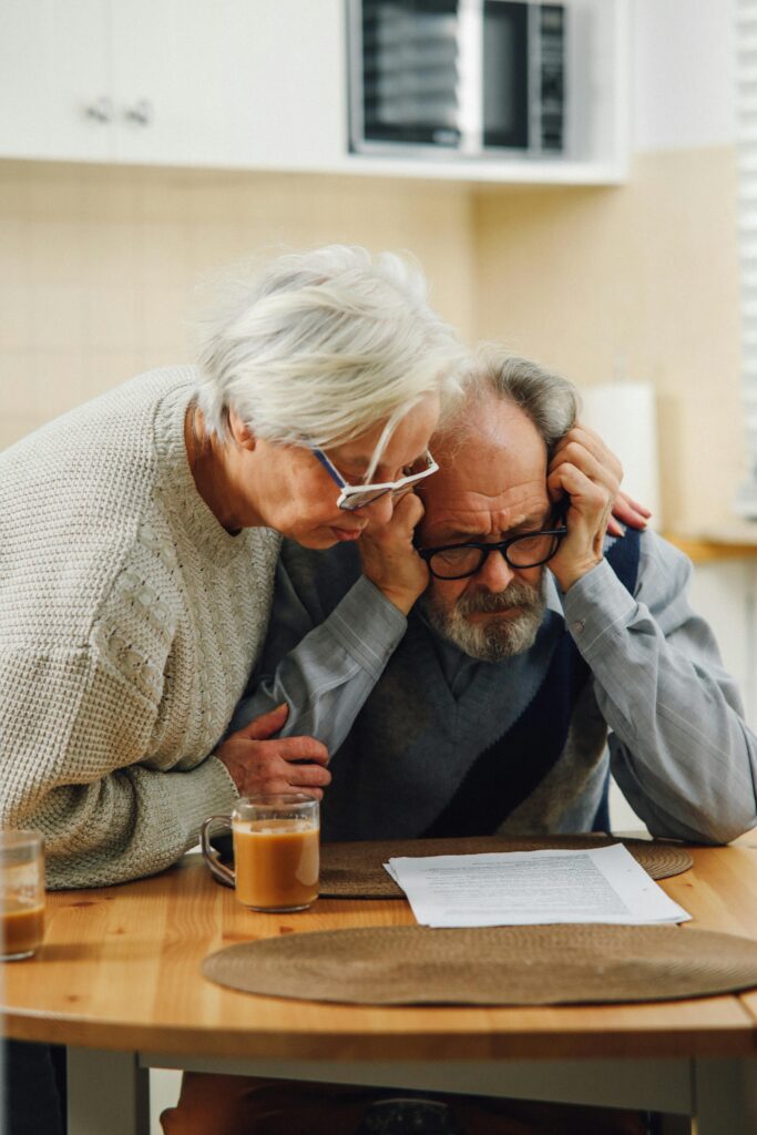 pexels-photo-6975208-6975208 A worried senior couple reviews important documents at their kitchen table.