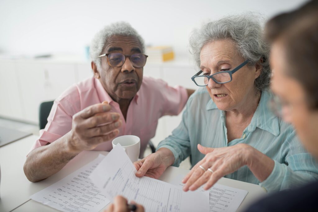 pexels-photo-8441778-8441778 Elderly couple discussing financial documents with a consultant in an office setting.