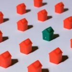 Miniature red and green monopoly houses on a white backdrop emphasizing contrast and arrangement.