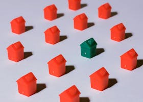 Miniature red and green monopoly houses on a white backdrop emphasizing contrast and arrangement.